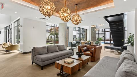 A renovated apartment complex in Atlanta with big open white interiors and many amenities and modern-style apartments with brown kitchens.