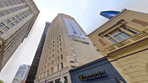 A large stucco and brick hotel building in the heart of downtown Atlanta with ornate facades near other tall buildings.