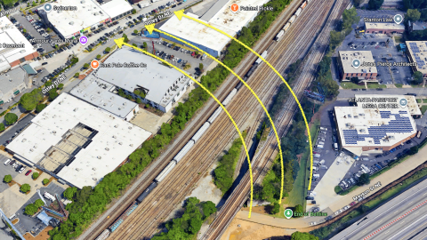 An image showing a pathway the Beltline trail in Atlanta with take near many buildings and warehouses over railroad lines.