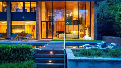 A photo of a modernized and large midcentury modern home in Atlanta near a large golf course with many trees around it.