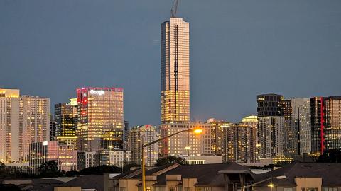 A photo in the evening of a large glassy new skyscraper in Atlanta under dark blue skies.