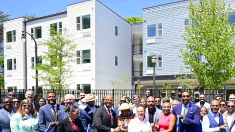 A large new building with modern exteriors and interiors and new trees in front where a ribbon-cutting has taken place.
