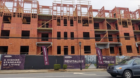 A photo of a large new apartment site north of Midtown Atlanta with new construction facing a street and renovated apartments with white interiors behind.