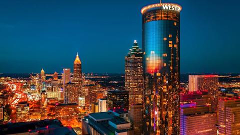 An image of many large glassy skycrapers on downtown Atlanta's skyline under blue night skies. 