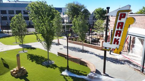 A park space shown under blue skies near many new buildings and sidewalks in the oldest part of downtown Atlanta.