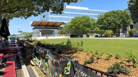 A photo of a large new greenspace and town square area in Atlanta under blue skies near many old buildings and trees.