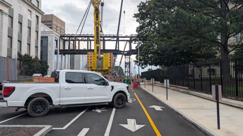 A photo of a large bridge project connecting two buildings in Atlanta near trees under gray skies.