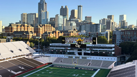 An image of changes plans to modernize a large old football stadium in the middle of a large city under blue skies, with nice fan suites added.