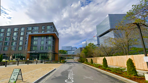 A rendering for new black-painted hotel under pink-gray skies north of Atlanta near many other new buildings. 
