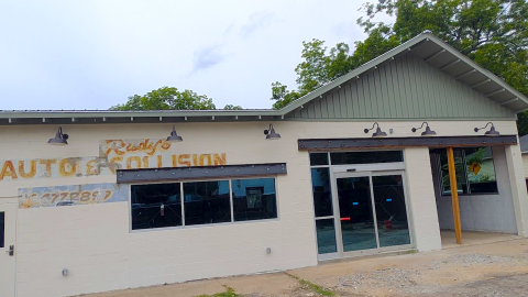 A photo of a former auto garage turned pizza shop under gray skies near many trees in Atlanta. 