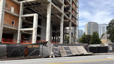 A photo of fallen scaffolding at a large construction site under blue skies in Midtown Atlanta, near a wide street.