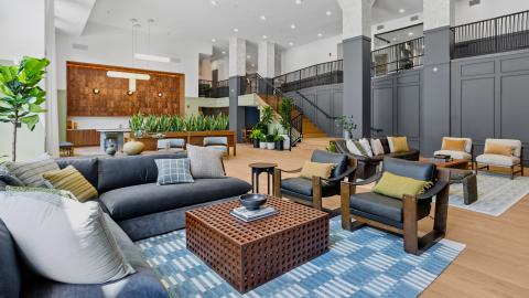 A new large apartment complex building and townhomes with modern interiors and a pool in the middle and brick facades. 