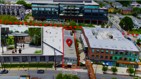 an image showing a large old brick building beside the Atlanta Beltline in a large district with many bars and restaurants in Atlanta. 