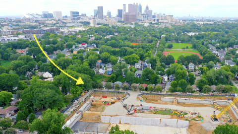 An aerial photo of a large rectangular park project in a leafy old Atlanta neighborhood near many houses and trees, under hazy blues skies.