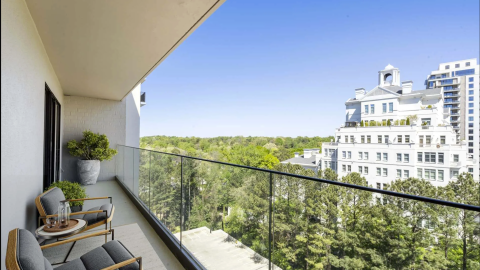 An image of a large renovated condo tower with modern interiors and large balconies in buckhead, Atlanta under blue skies with a pool in back.