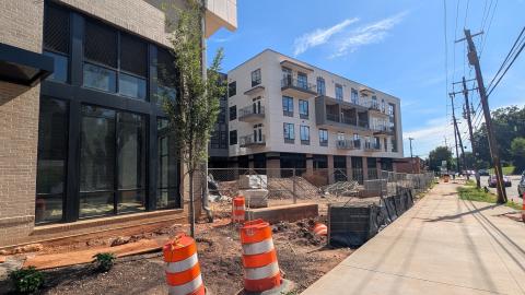 A phot of a large new construction site with two white new buildings connected by a black multilevel building under blue skies near muddy ground in Decatur, east of Atlanta.