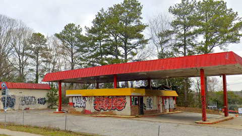 A blighted gas station property covered with graffiti under gray skies in Atlanta Georgia.
