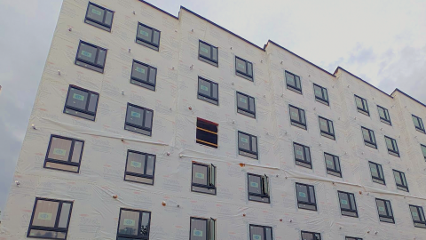 a photo of a large white building under construction under gray skies in Atlanta, along a wide street and parking lot.