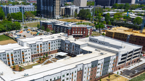 A photo of a large new apartment housing complex west of Midtown and downtown Atlanta near wide streets and many trees.