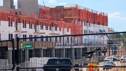 An image of a large mall redevelopment site where multiple buildings including apartments and a Publix grocery store are rising under blue skies.