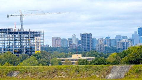 A photo of a large new high-rise tower in Atlanta near many trees with the concrete infrastructure installed under cloudy skies.