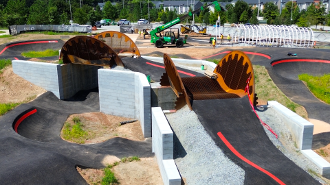 An image of a large new bike park with black trails and bridges and many jumps in Westside Atlanta near a forest.