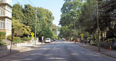 An image of an Atlanta street under blue skies with buildings and trees on both sides today.