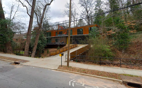 A modern house with airy white interiors built of corten steel on the outside with a bridge in front.