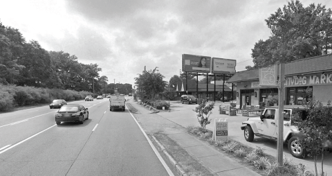 An image of a wide highway running through a city with many trees on either side.